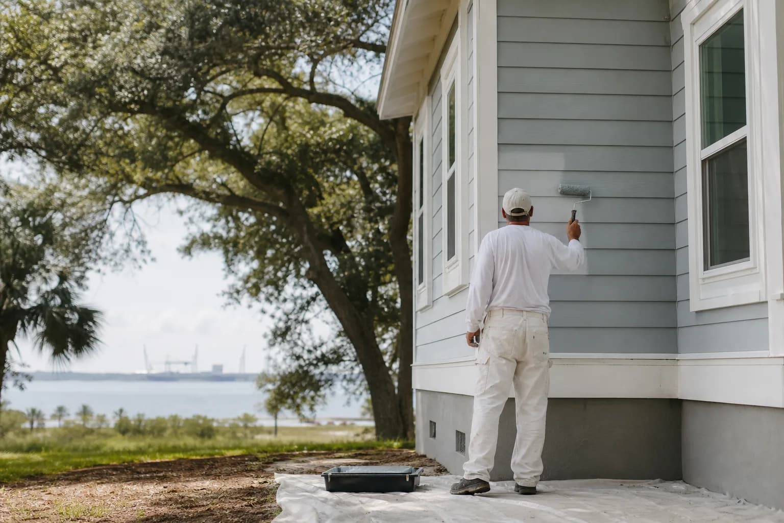 Painter applying a quality acrylic exterior finish to a home near Mobile Bay, illustrating the best exterior paint for salt air and humidity in Mobile, AL