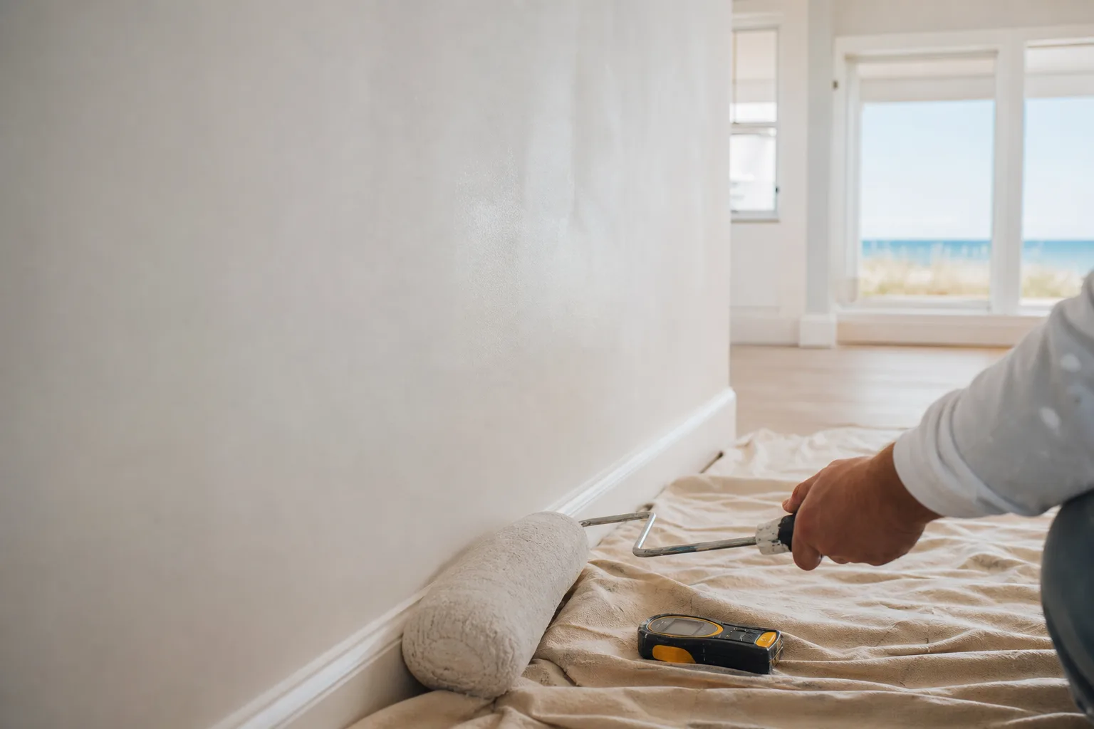 Freshly painted interior wall drying in a humid coastal Alabama room with a paint roller and moisture meter nearby.