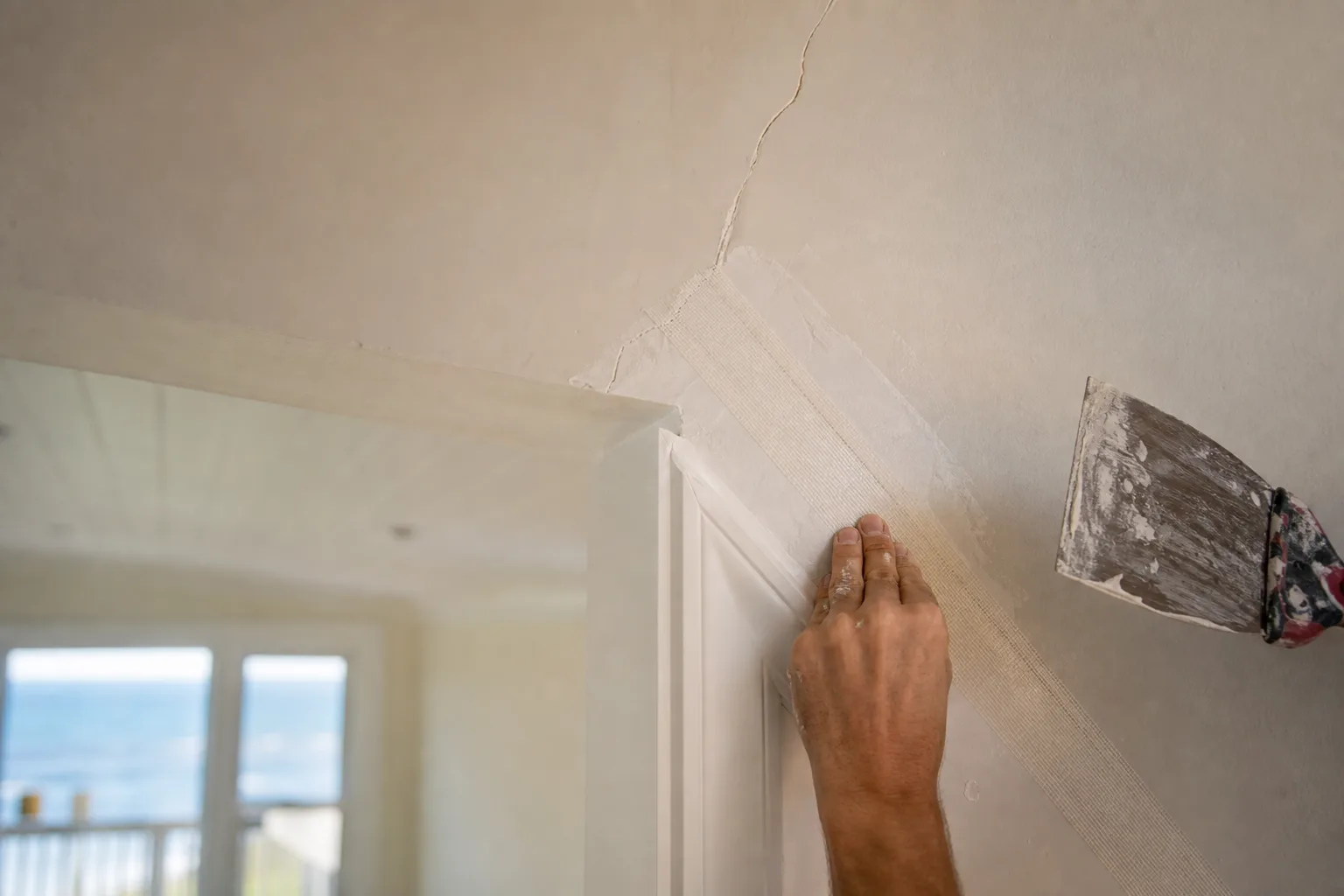 Re-taping a recurring stress crack above a door frame so the drywall repair won't come back