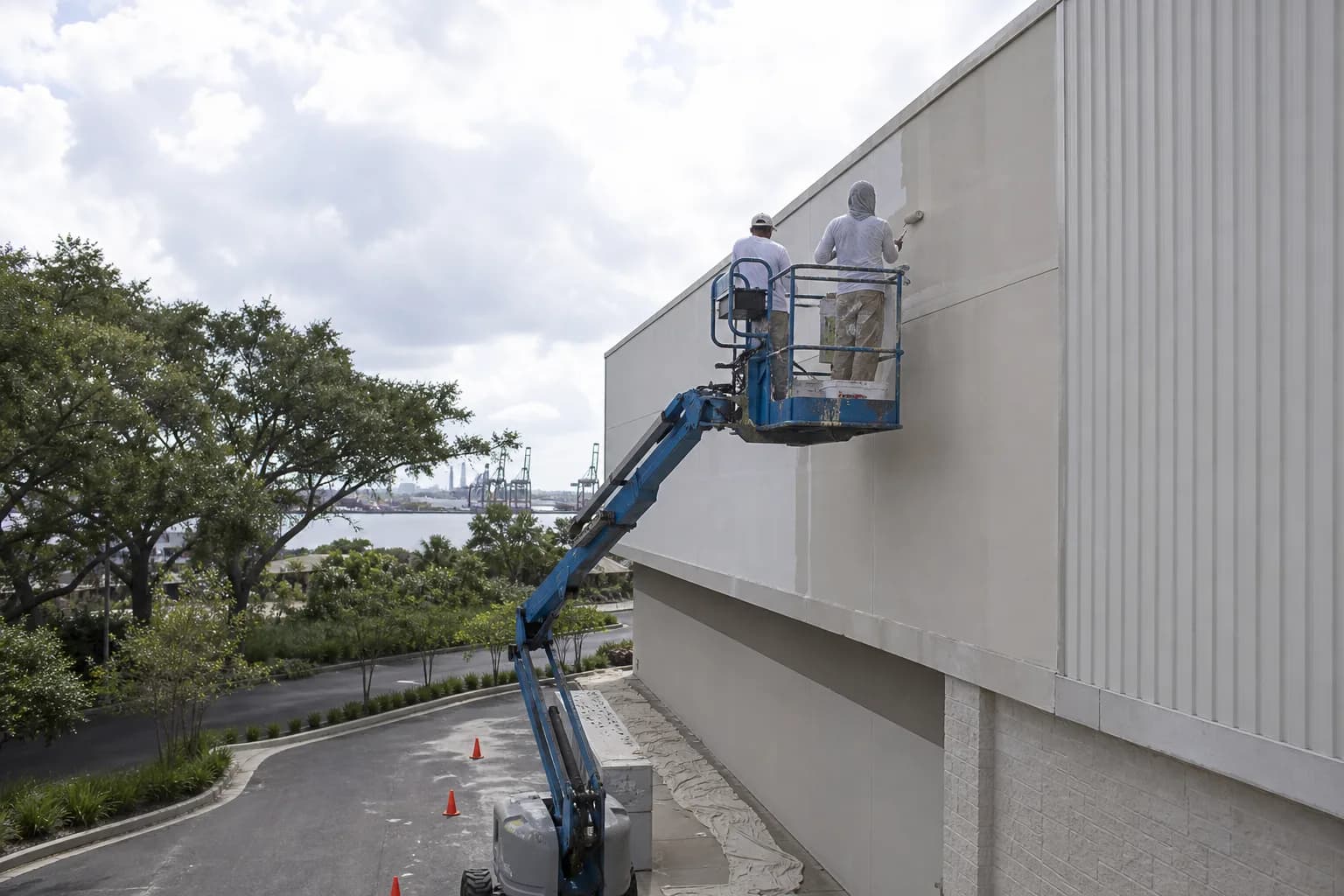 Crew on a lift applying a salt-air-resistant coating system to a commercial building exterior on the Gulf Coast