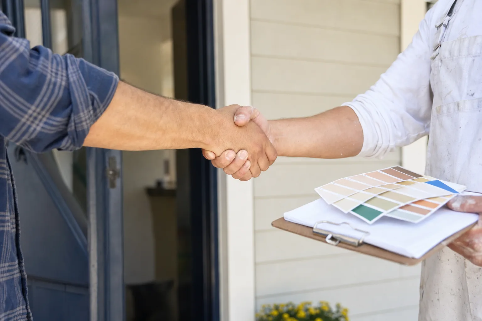 Homeowner and painter shaking hands at a front door, hands only
