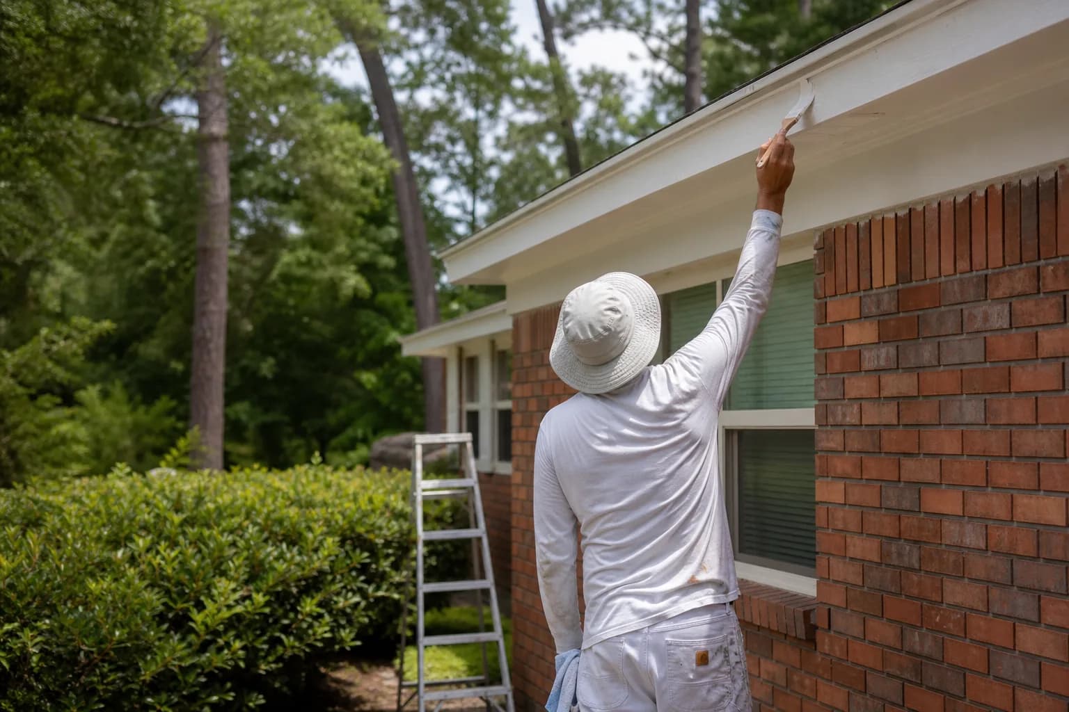 House painters working on a mid-century brick ranch home in Tillman's Corner, Alabama