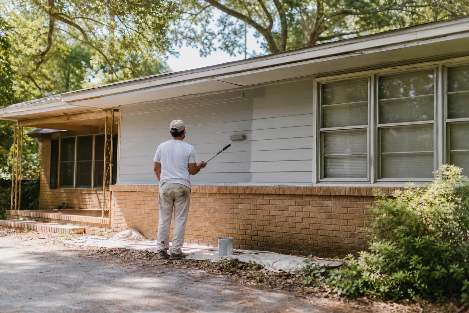 House painter repainting a mid-century ranch home exterior in Toulminville, Mobile, AL