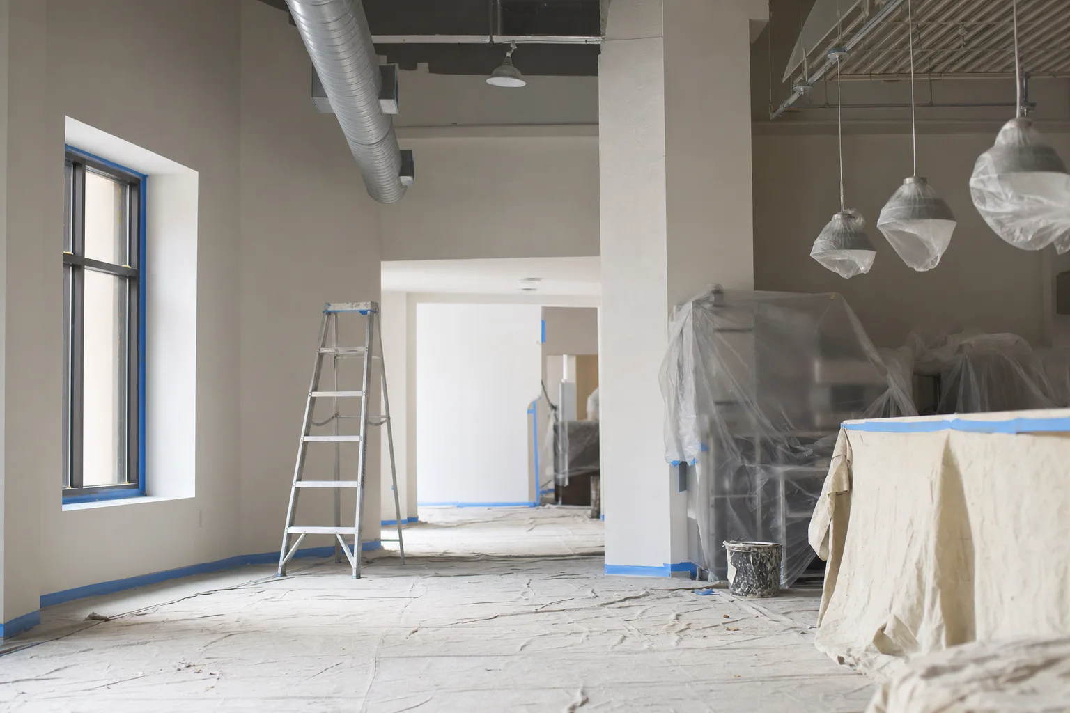 Commercial space masked and covered with drop cloths before painting