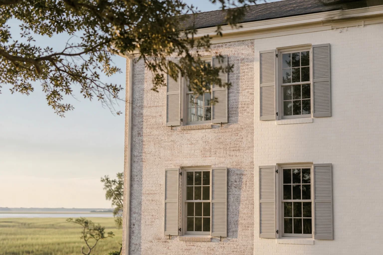Side-by-side comparison of limewashed brick and solid painted brick on a coastal home facade