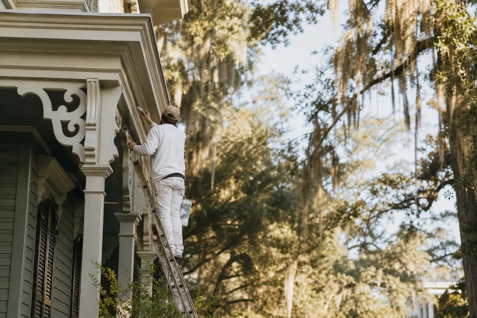 Painting a historic home in Mobile — cutting in fresh exterior paint on the ornate eave bracket of an Italianate house