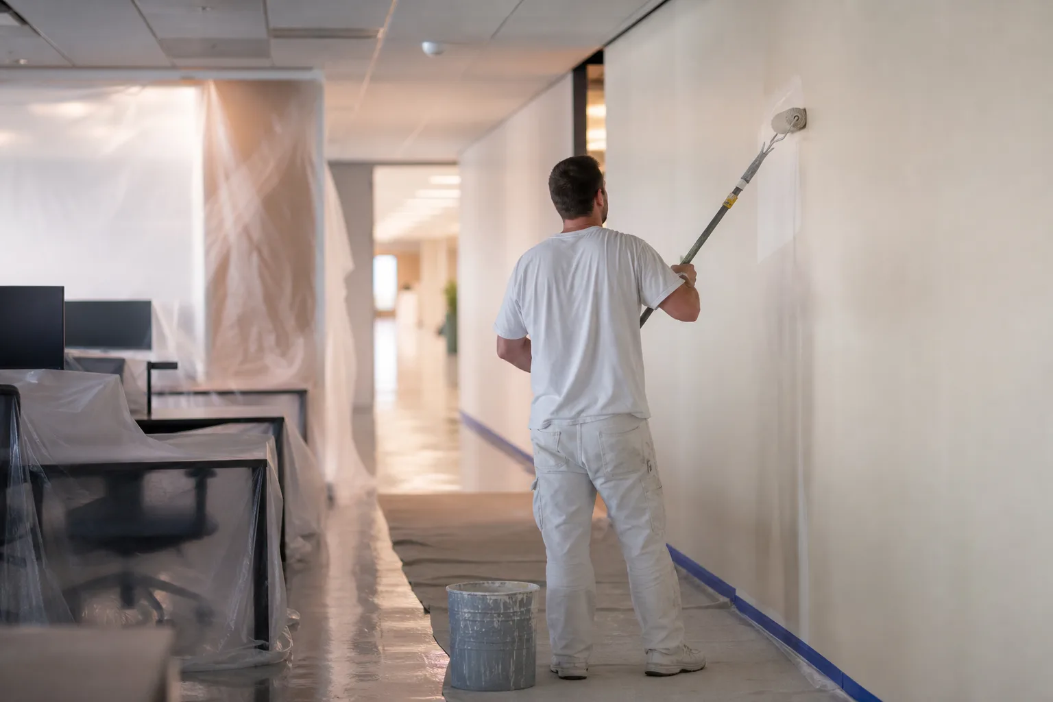 Painting an occupied commercial space after hours: rolling an office corridor with the work zone sealed off