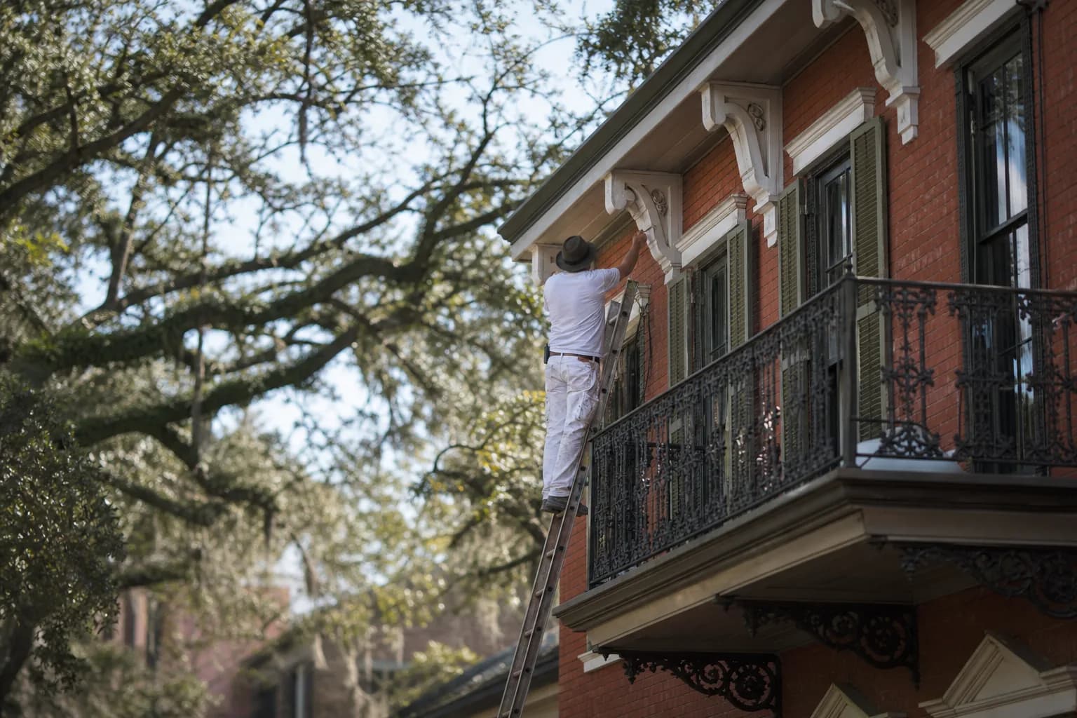 Painting ornate Italianate eave brackets and cast-iron on a Victorian townhouse in Mobile's De Tonti Square