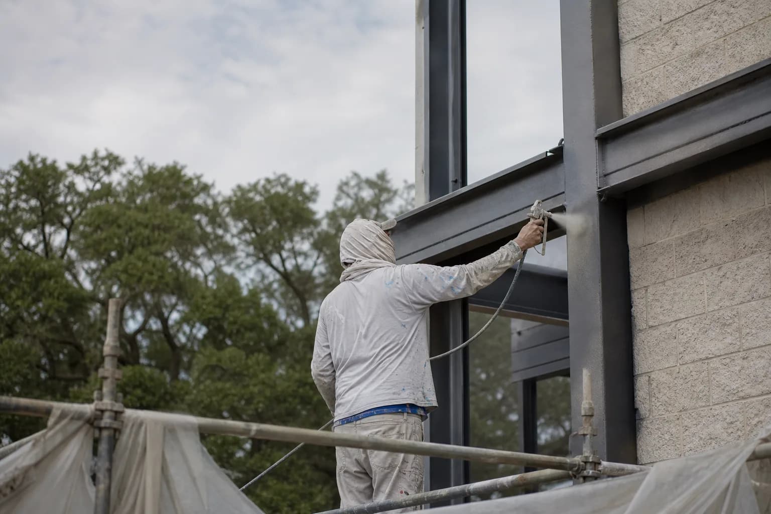 Painter applying a specialty coating to steel and masonry on a Gulf Coast commercial building